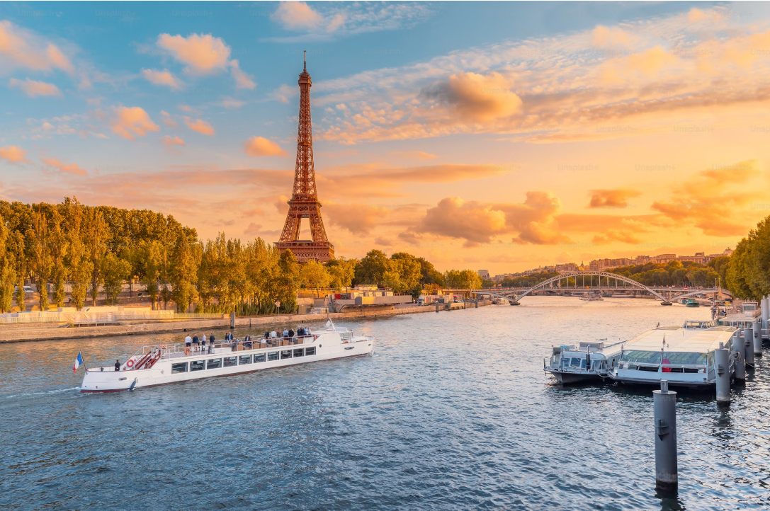 La Tour Eiffel dans les rayons du soleil avec au premier plan la Seine avec des bateaux de tourisme